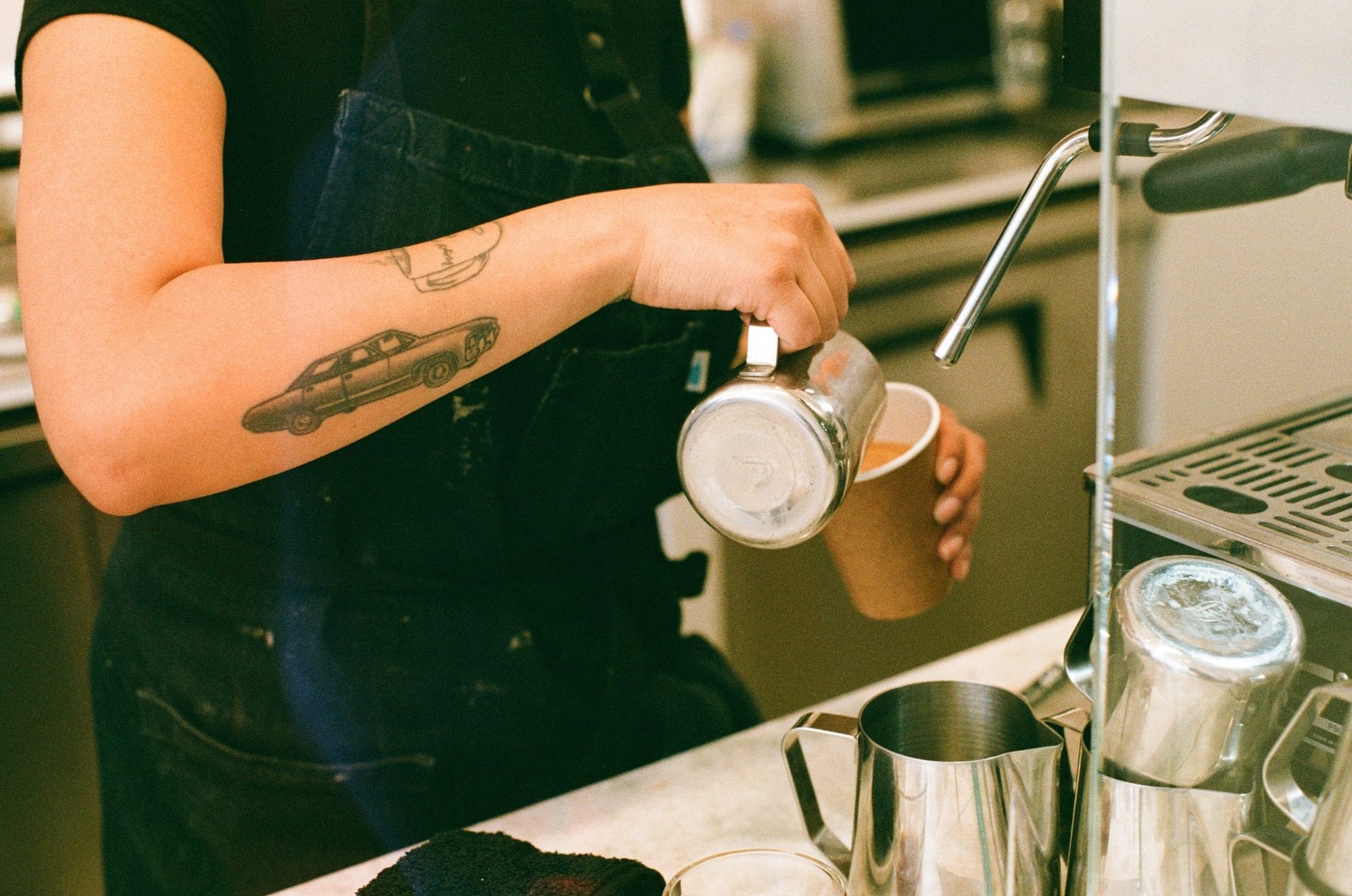 A barista pouring milk behind the counter